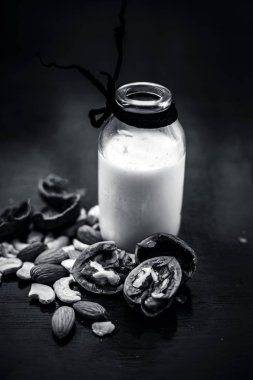 Kabuk ceviz ile cam bir şişe de çiğ süt kapatın ve ahşap yüzeye çatlamış.