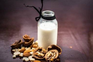 Kabuk ceviz ile cam bir şişe de çiğ süt kapatın ve ahşap yüzeye çatlamış.