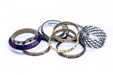 Close up of mixed ornaments or jeweleries to wear them in hands isolated on white which are bangles and some other band like objects. clipart
