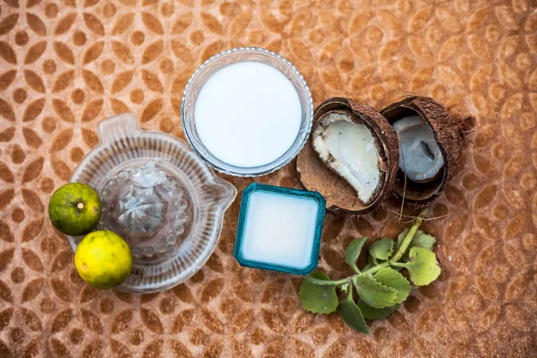 Hair therapy or hair growth remedy on wooden surface in a glass bowl consisting of coconut milk well mixed with lemon juice with raw ingredients also.