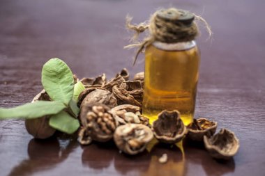 Ahşap yüzeyüzerinde ham duvar fındık ile şeffaf bir cam şişe de bitkisel organik ayıklanmış ceviz yağı yakın.