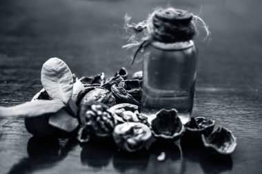 Ahşap yüzeyüzerinde ham duvar fındık ile şeffaf bir cam şişe de bitkisel organik ayıklanmış ceviz yağı yakın.