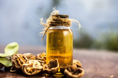 Ahşap yüzeyüzerinde ham duvar fındık ile şeffaf bir cam şişe de bitkisel organik ayıklanmış ceviz yağı yakın.