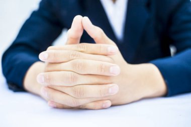 Elleri masanın üstünde işadamının kırpılmış görüntüsü.