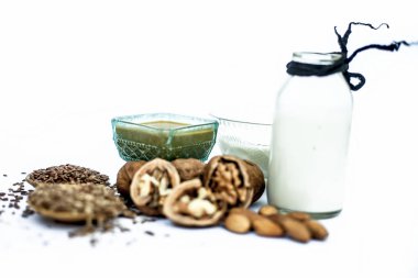 Keten tohumu veya alsi, badem, yoğurt ve süt ile birlikte yüz maskesi veya ceviz yüz paketi yakın bir cam kase tüm ham maddeler beyaz izole.