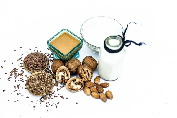 Close up of face mask or face pack of walnut along with flax seed or alsi, almonds,yogurt and milk in a glass bowl   entire raw ingredients isolated on white.