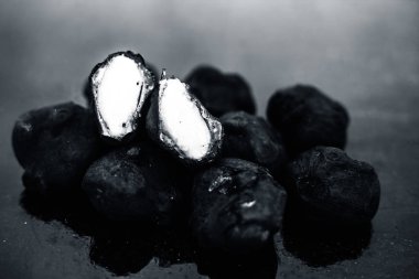 Bunlardan biri kesilmiş siyah renkli ahşap yüzey üzerinde taze organik çiğ su kestane yakın.