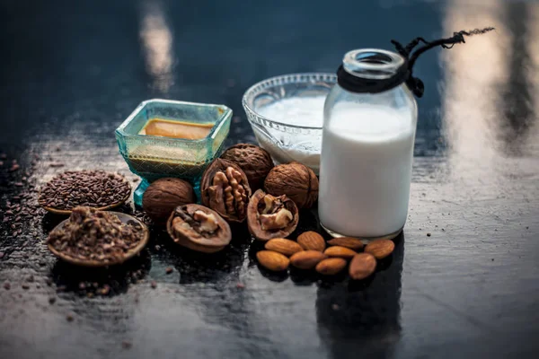 Close up of face mask or face pack of walnut along with flax seed or alsi, almonds,yogurt and milk in a glass bowl   entire raw ingredients on wooden surface.;