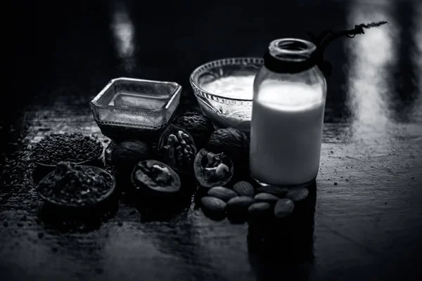 Close up of face mask or face pack of walnut along with flax seed or alsi, almonds,yogurt and milk in a glass bowl   entire raw ingredients on wooden surface.;