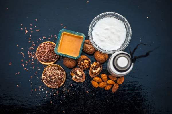 Close up of face mask or face pack of walnut along with flax seed or alsi, almonds,yogurt and milk in a glass bowl   entire raw ingredients on wooden surface.;