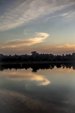 Ağaçlar ve bulutlar ile bir göl üzerinden gün batımı alacakaranlık zaman çekim.