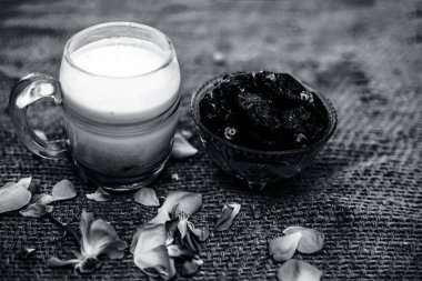 Tarih süt veya kuru meyve süt yapmak için kullanılan gunny çanta üzerinde bir bardak tarih ve çiğ süt yakın.