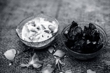 Şeffaf bir cam kase de popüler Hint & Asya kış tatlısı yakın çekim yani Khajor ka halwa veya kahverengi renkli yüzeyüzerinde bazı gül yaprakları ile çiğ hurma ve bazı gül yaprakları ile şekerleme tarihleri.