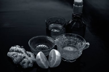 Ahşap yüzeyüzerinde şeffaf bir fincan viski, zencefil, bal, su, limon ve nane oluşan bitkisel yeşil çay yakın.