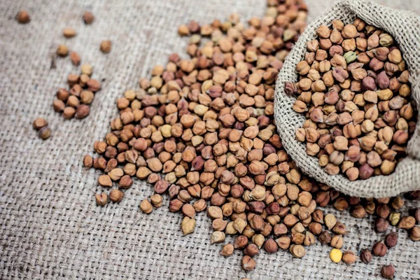 Close up shot of chickpea or chana or gram or Cicer arietinum in a gunny bag on a brown colored background.