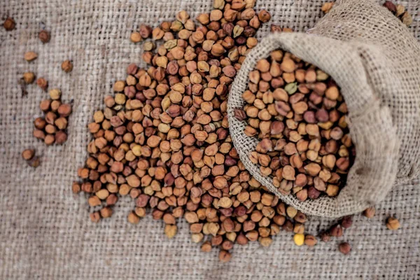 Close up shot of chickpea or chana or gram or Cicer arietinum in a gunny bag on a brown colored background.