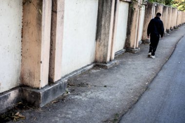 Bir insan figürü erkek genç duvar ana hatları geçerek rads üzerinde yürüyen siluet. Minimalist görünüm.