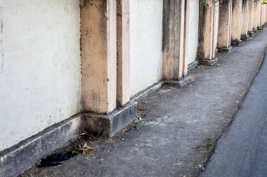 Güneş ışınları ve duvarda önde gelen çizgiler ve yolda bazı sonbahar yaprakları ile gündoğumu sırasında alınan boş yollar.