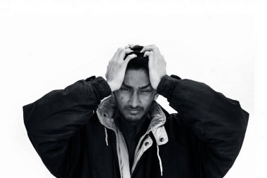 Kahverengi renkli gömlek ve siyah renkli ceket giyen genç sakallı bir adamın kafasını tutarak stresi ifade eden portre fotoğrafı.