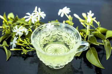 Ham çiçekleri ile cam bir fincan ahşap yüzeyinde Hint yasemin çiçek veya juhi veya Jasminum Auriculatum çay yakın.