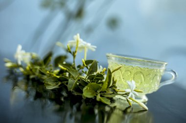 Ham çiçekleri ile cam bir fincan ahşap yüzeyinde Hint yasemin çiçek veya juhi veya Jasminum Auriculatum çay yakın.