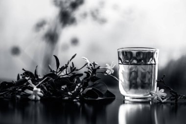 Ham çiçeklerile şeffaf bir cam ahşap yüzeyinde Hint yasemin çiçeği veya juhi veya Jasminum Auriculatum özü yakın.