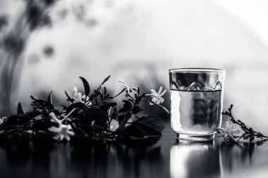 Ham çiçeklerile şeffaf bir cam ahşap yüzeyinde Hint yasemin çiçeği veya juhi veya Jasminum Auriculatum özü yakın.