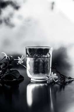 Ham çiçeklerile şeffaf bir cam ahşap yüzeyinde Hint yasemin çiçeği veya juhi veya Jasminum Auriculatum özü yakın.