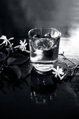 Ham çiçeklerile şeffaf bir cam ahşap yüzeyinde Hint yasemin çiçeği veya juhi veya Jasminum Auriculatum özü yakın.