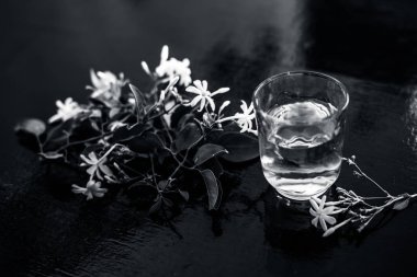 Ham çiçeklerile şeffaf bir cam ahşap yüzeyinde Hint yasemin çiçeği veya juhi veya Jasminum Auriculatum özü yakın.