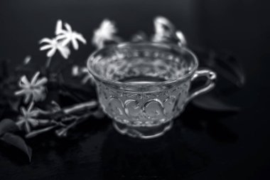 Ham çiçekleri ile cam bir fincan ahşap yüzeyinde Hint yasemin çiçek veya juhi veya Jasminum Auriculatum çay yakın.
