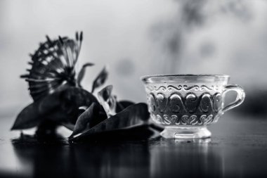 Bir cam bardak onun çıkarılan yararlı detoksifiye çay ile ahşap yüzeyüzerinde kırmızı renkli pentas çiçek veya Mısır Star Çiçek veya yasemin yakın.