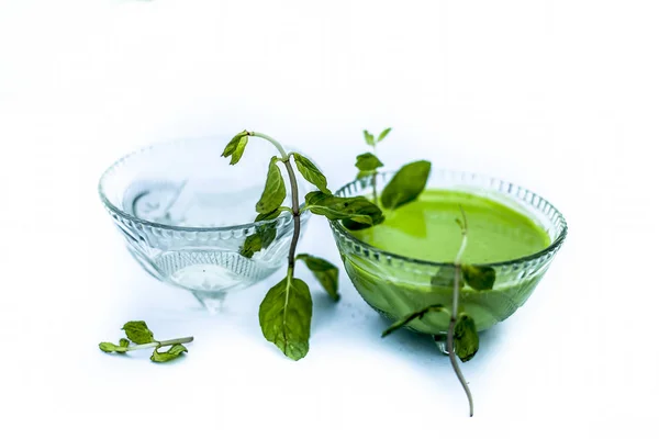 Best home remedy or treatment to reduce rashes isolated on white consisting of mint and water in a glass bowl with raw mint leaves and its juice or pulp and water.