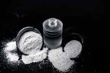 Ahşap yüzeyüzerinde ham haşhaş tohumu ve toz ile küçük bir cam şişe haşhaş tohumu veya khus khus organik yağ yakın.