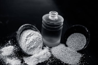 Ahşap yüzeyüzerinde ham haşhaş tohumu ve toz ile küçük bir cam şişe haşhaş tohumu veya khus khus organik yağ yakın.