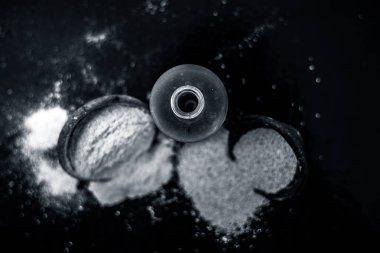 Ahşap yüzeyüzerinde ham haşhaş tohumu ve toz ile küçük bir cam şişe haşhaş tohumu veya khus khus organik yağ yakın.