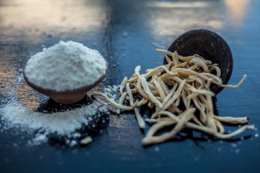 Popüler Hint & Asya ayurveda organik bitki musli Safed Moosli/ Shaqaqule/ Dholi Musli/ Khiruva/ Shedheveli/ Swetha Musli/ Taniravi Thang/ tozlu ahşap yüzeyüzerinde kil bir kapta.