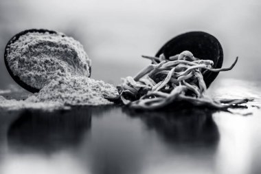 Popüler Hint & Asya ayurveda organik bitki musli Safed Moosli/ Shaqaqule/ Dholi Musli/ Khiruva/ Shedheveli/ Swetha Musli/ Taniravi Thang/ tozlu ahşap yüzeyüzerinde kil bir kapta.