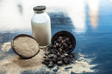 Popüler Hint & Asya ayurveda organik bitki musli veya Chlorophytum borivilianum veya Curculigo orkioidler veya kali moosli süt dolu şeffaf bir cam şişe ile ahşap yüzey üzerinde bir kil.