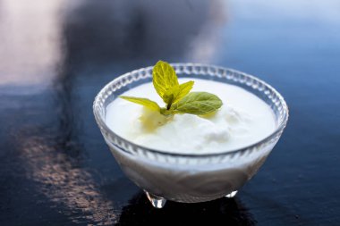 Ahşap yüzeyde dekorasyon için üst nane yaprağı ile birlikte cam bir kapta ham organik lor yakın.