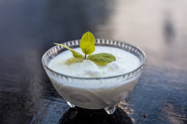 Ahşap yüzeyde dekorasyon için üst nane yaprağı ile birlikte cam bir kapta ham organik lor yakın.