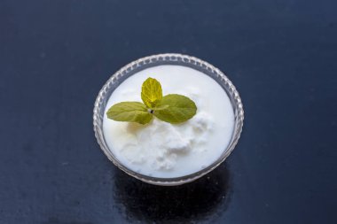 Ahşap yüzeyde dekorasyon için üst nane yaprağı ile birlikte cam bir kapta ham organik lor yakın.