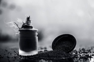 Ham organik bitkisel baharat Hardal tohumu veya sarso veya rai veya Brassica nigra, şeffaf bir cam şişe onun çıkarılan uçucu yağ ile ahşap yüzeyüzerinde bir kil kase içinde.