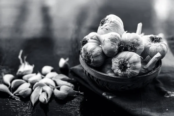 Raw organic garlic bulbs or lasun or Allium sativum in a hamper or basket on wooden surface.