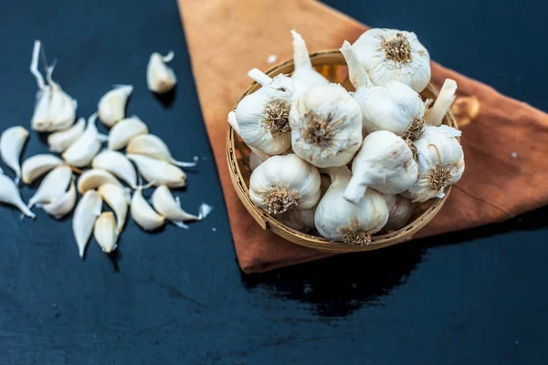 Raw organic garlic bulbs or lasun or Allium sativum in a hamper or basket on wooden surface.