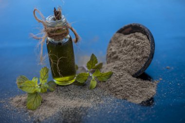 Ayurveda bitki brahmi veya Waterhyssop küçük bir şeffaf cam şişe içinde özü ile ahşap yüzey üzerinde toz ile birlikte.