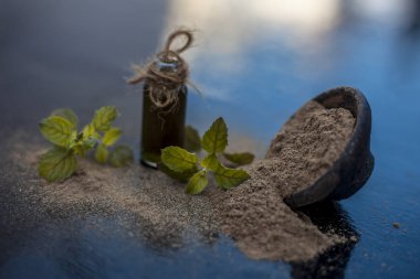 Ayurveda bitki brahmi veya Waterhyssop küçük bir şeffaf cam şişe içinde özü ile ahşap yüzey üzerinde toz ile birlikte.