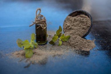 Ayurveda bitki brahmi veya Waterhyssop küçük bir şeffaf cam şişe içinde özü ile ahşap yüzey üzerinde toz ile birlikte.