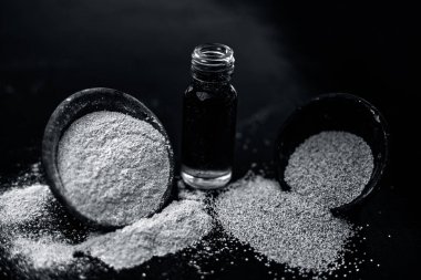 Küçük şeffaf cam şişe onun çıkarılan bitkisel ve organik uçucu yağ veya özü ile Haşhaş tohumu veya afyon haşhaş veya ekmek tohumu haşhaş dolu ahşap yüzeyüzerinde Kil kase.