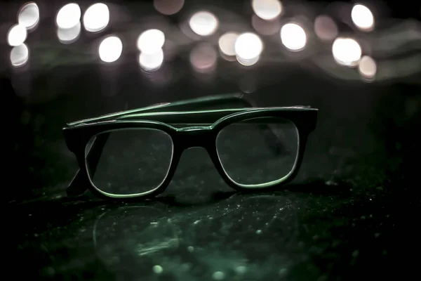 Black colored or black framed spectacles or reading glasses on wooden surface.